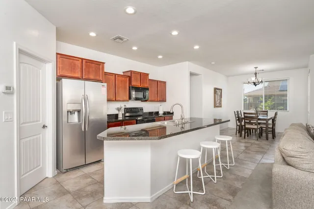 a kitchen with stainless steel appliances kitchen island granite countertop a refrigerator and a stove top oven