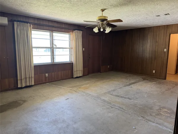 an empty room with a chandelier fan and windows