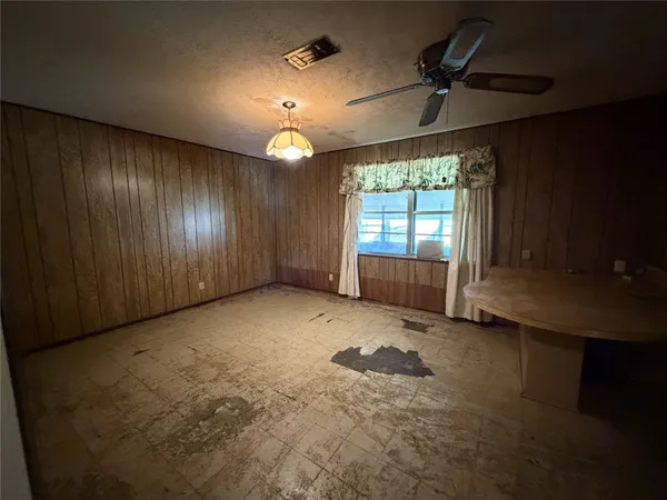 en empty room with windows and chandelier fan