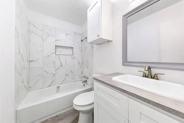 a bathroom with a granite countertop sink a toilet a mirror and bathtub
