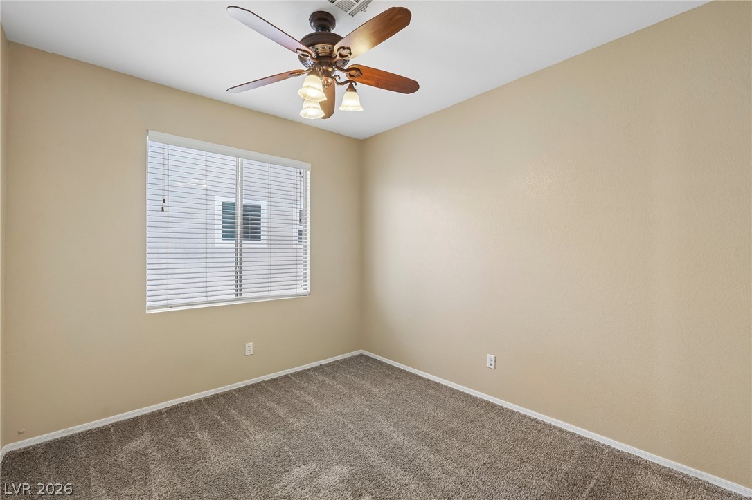 1727 Millstream Way Henderson, NV 89074 - Photo 29 of 46 A window with horizontal blinds fills this cozy bedroom, illuminated by a classic ceiling fan.