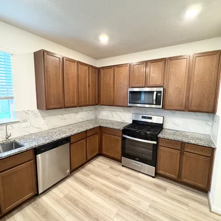 a kitchen with granite countertop wooden cabinets a stove top oven and stainless steel appliances