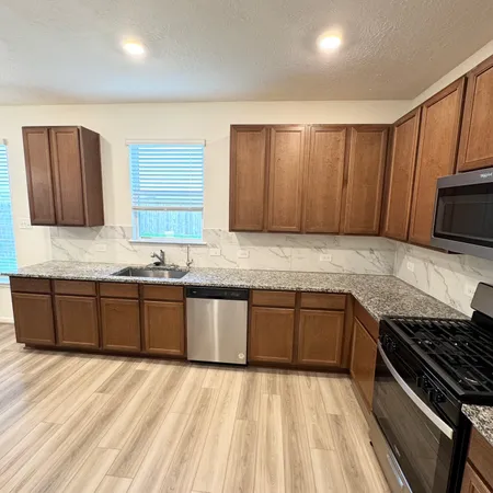 a kitchen with granite countertop wooden cabinets a stove top oven and granite counter tops