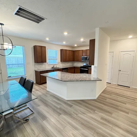 a large kitchen with stainless steel appliances granite countertop a stove a sink and a refrigerator