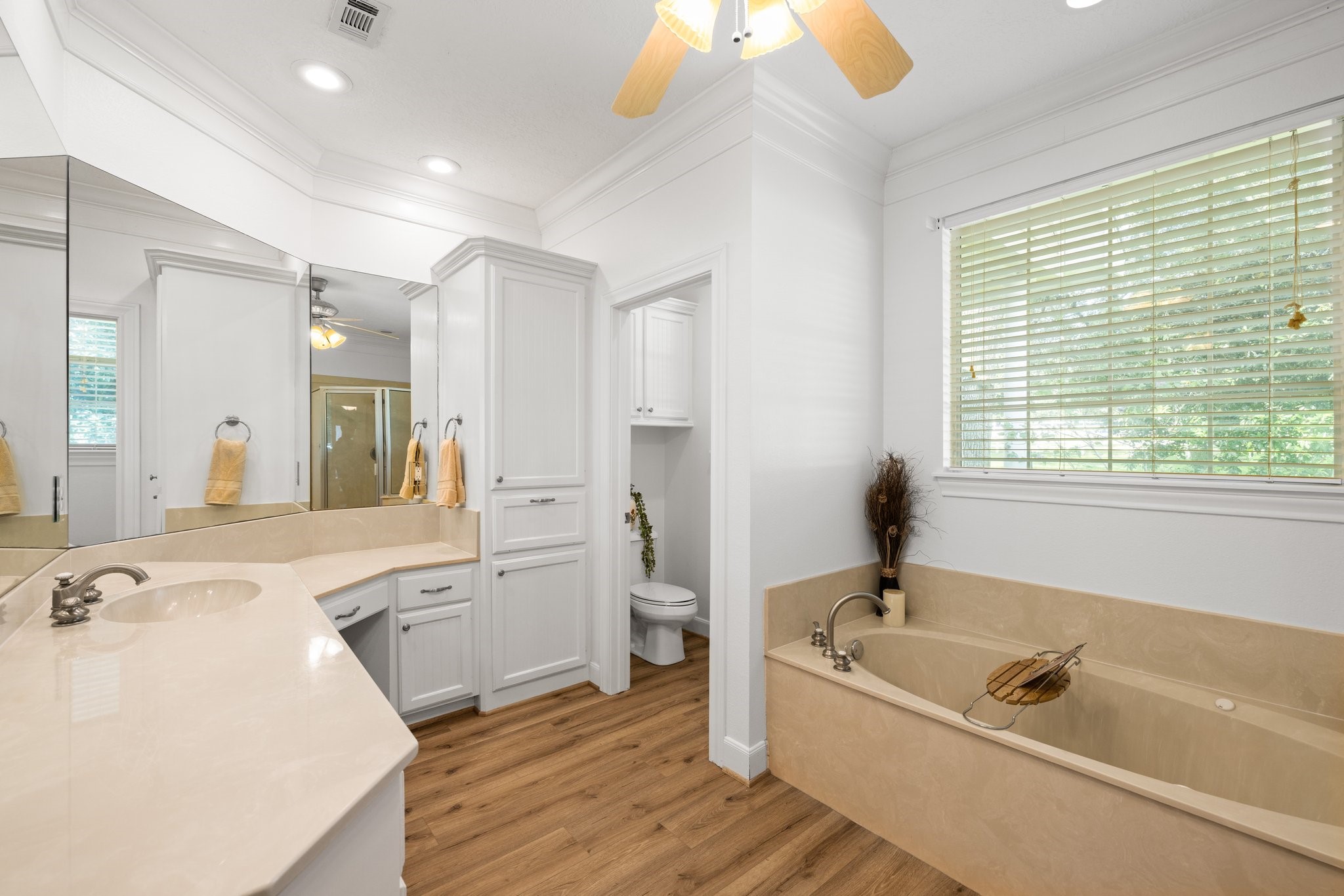 34310 High Point Drive Magnolia, TX 77355 - Photo 16 of 48 This elegant primary bathroom boasts a spacious design with a large vanity, ample storage, a relaxing tub, and warm vinyl plank flooring—perfect for unwinding after a long day.