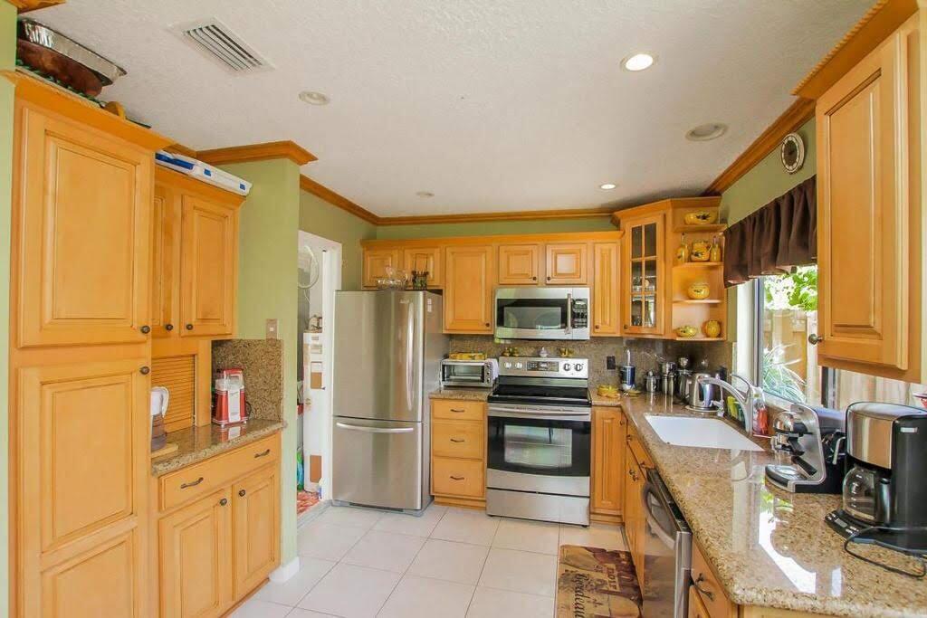 9709 Sunny Isle Circle Boca Raton, FL 33428 - Photo 3 of 21 a kitchen with stainless steel appliances a refrigerator and a stove top oven