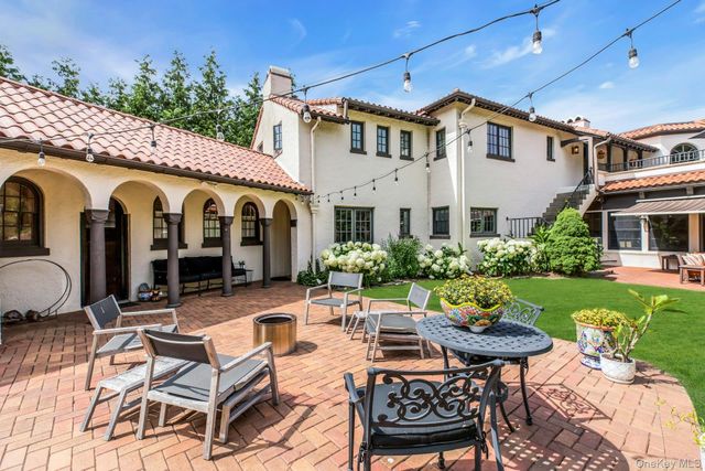 a view of a patio with couches table and chairs potted plants and large tree