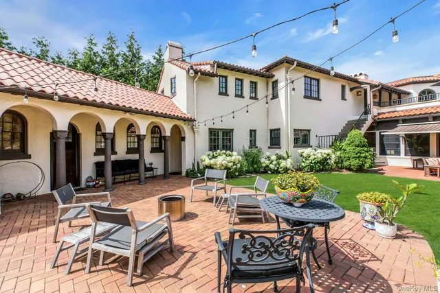 a view of a patio with couches table and chairs potted plants and large tree