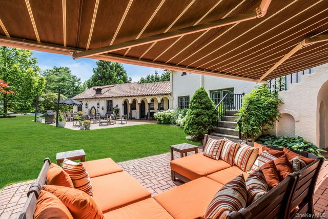 a view of a backyard with couches plants and large trees