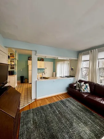 a living room with a bed and a dresser with wooden floor