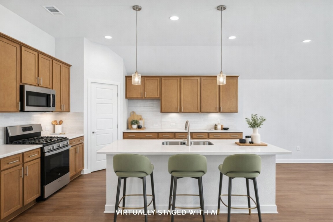 707 Hackberry Branch Magnolia, TX 77354 - Photo 2 of 50 a kitchen with stainless steel appliances granite countertop a sink a stove a kitchen island with chairs and wooden cabinets