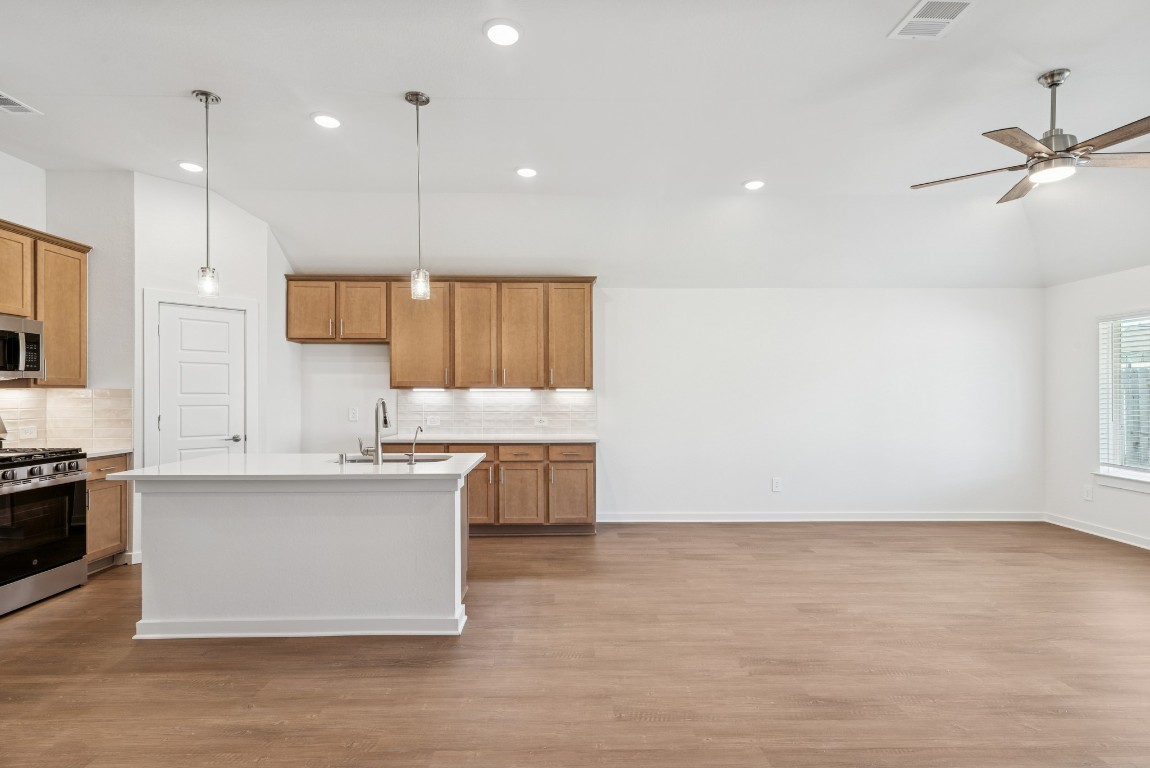 707 Hackberry Branch Magnolia, TX 77354 - Photo 31 of 50 a large kitchen with kitchen island a stove a sink a center island and wooden floor