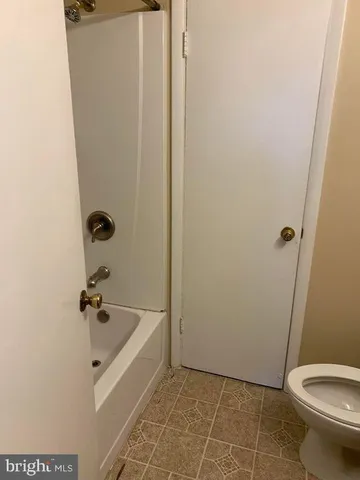 a bathroom with a granite countertop toilet and a tub