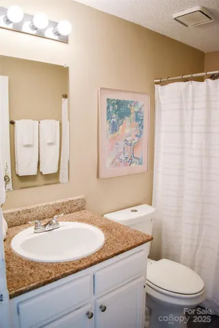 a bathroom with a granite countertop sink a toilet and a mirror