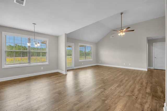 a view of an empty room with window and chandelier fan