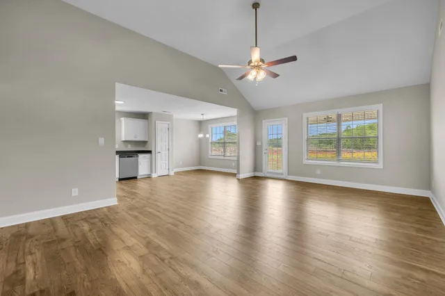 a view of an empty room with a ceiling fan and wooden floor