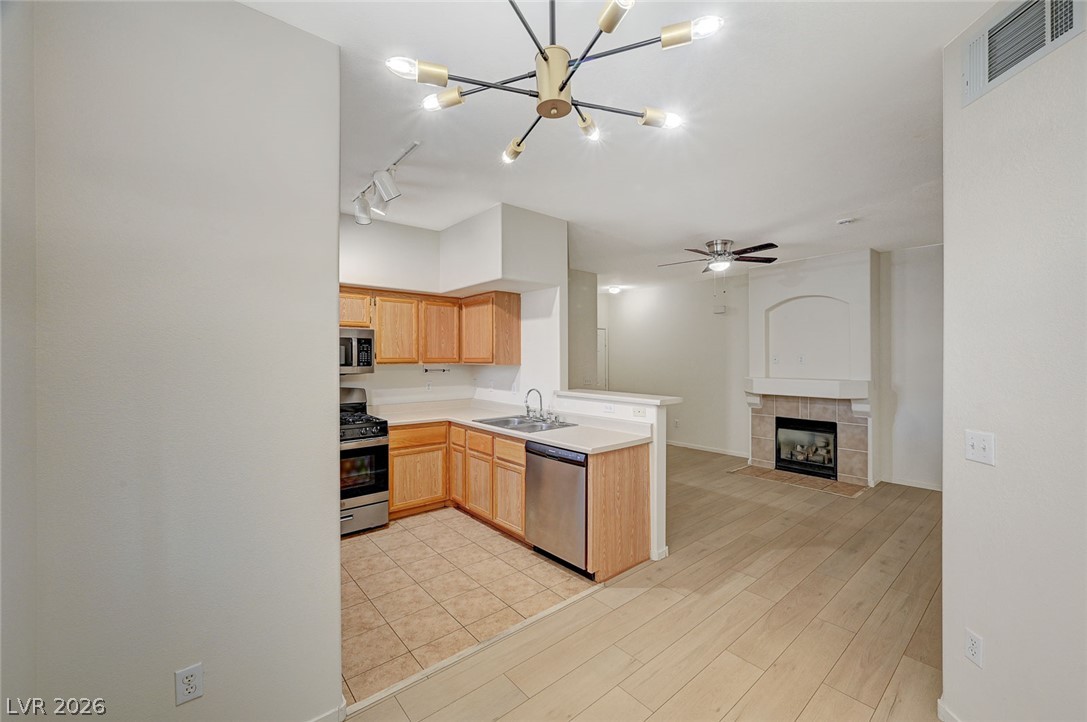 9050 West Warm Springs Road, Unit 1147 Las Vegas, NV 89148 - Photo 11 of 36 An open-concept living area features a stylish kitchen, a cozy fireplace, and rich flooring.