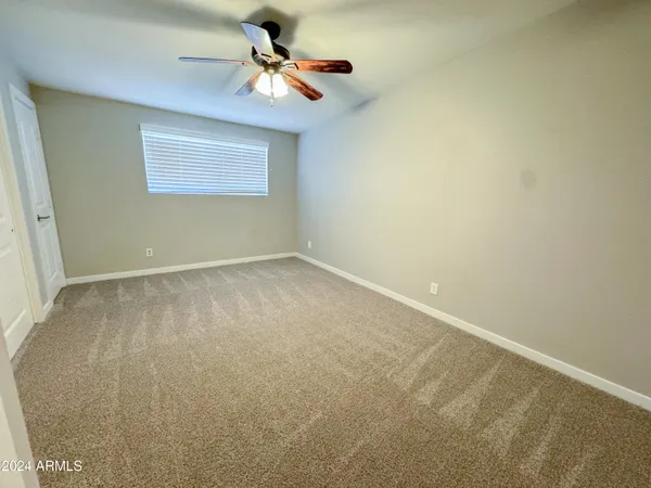 an empty room with a chandelier fan and windows