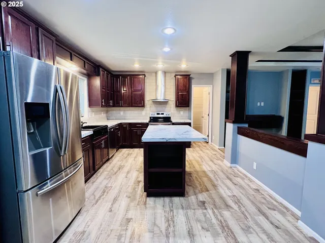 a kitchen with stainless steel appliances granite countertop wooden cabinets and a stove top oven