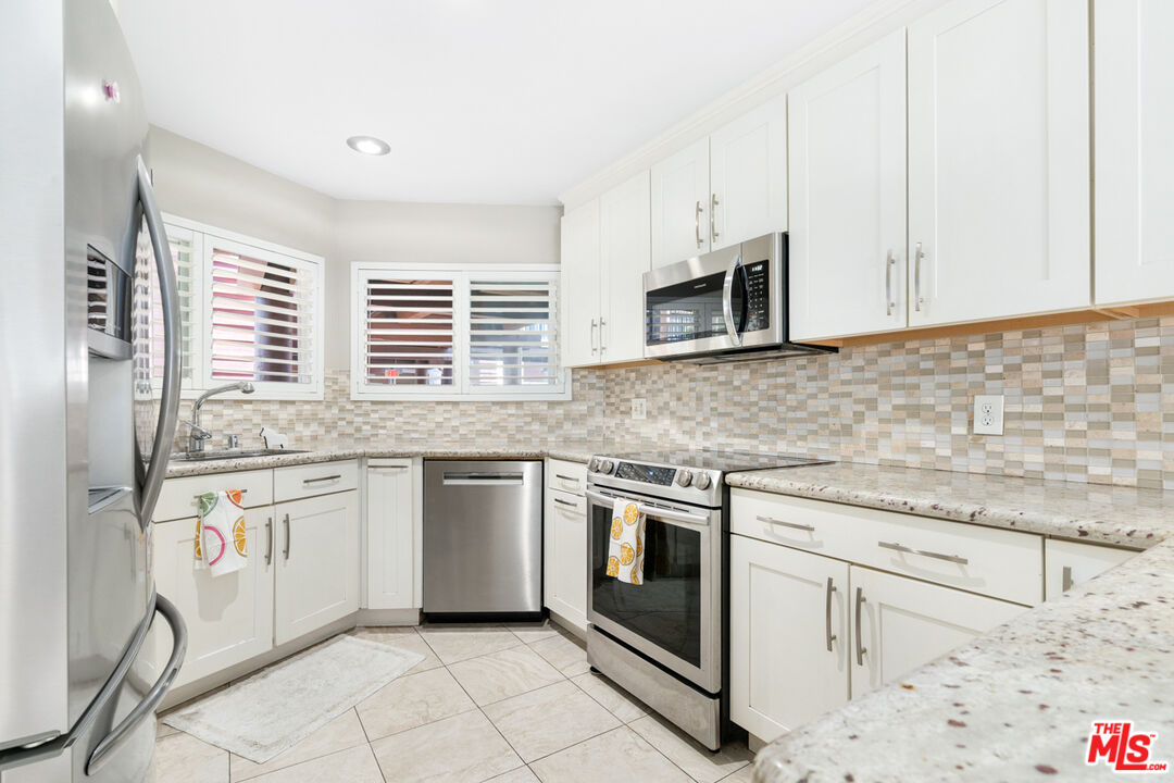 4150 Vía Dolce, Unit 236 Venice, CA 90292 - Photo 10 of 26 a kitchen with stainless steel appliances granite countertop a stove a sink and a microwave