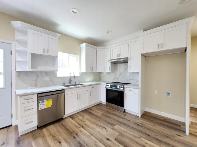 a kitchen with granite countertop white cabinets and stainless steel appliances