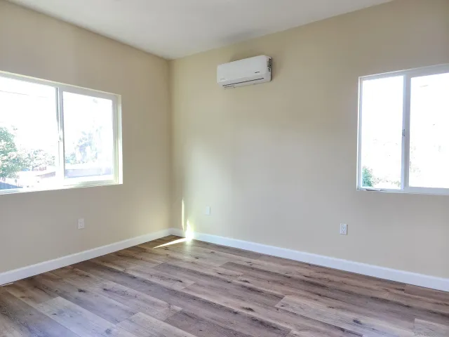 an empty room with wooden floor and windows