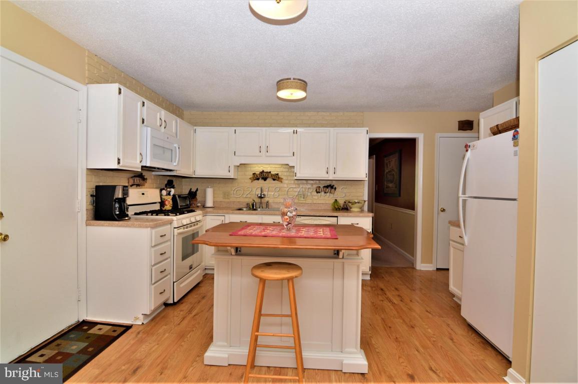 1 Mist Flower Road Ocean Pines, MD 21811 - Photo 14 of 66 a kitchen with stainless steel appliances granite countertop a refrigerator a stove a sink and white cabinets with wooden floor