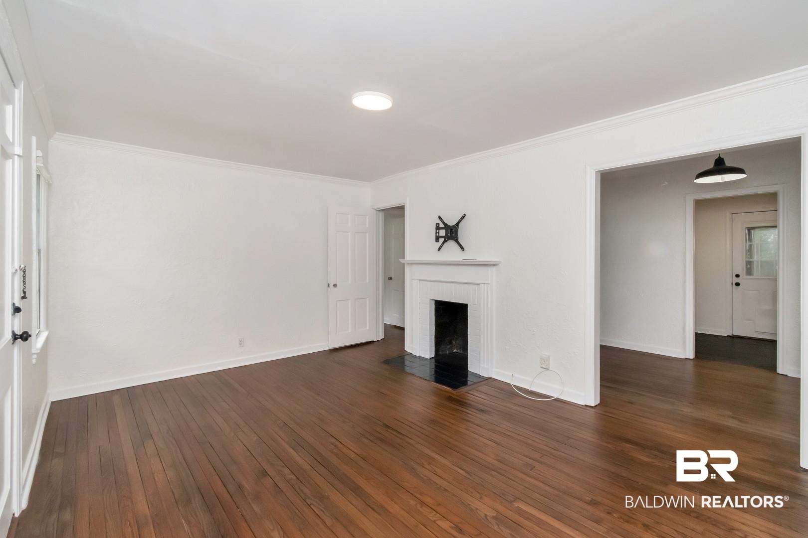 208 Morgan Avenue Mobile, AL 36606 - Photo 5 of 27 Unfurnished living room with a brick fireplace, ornamental molding, and dark wood-type flooring