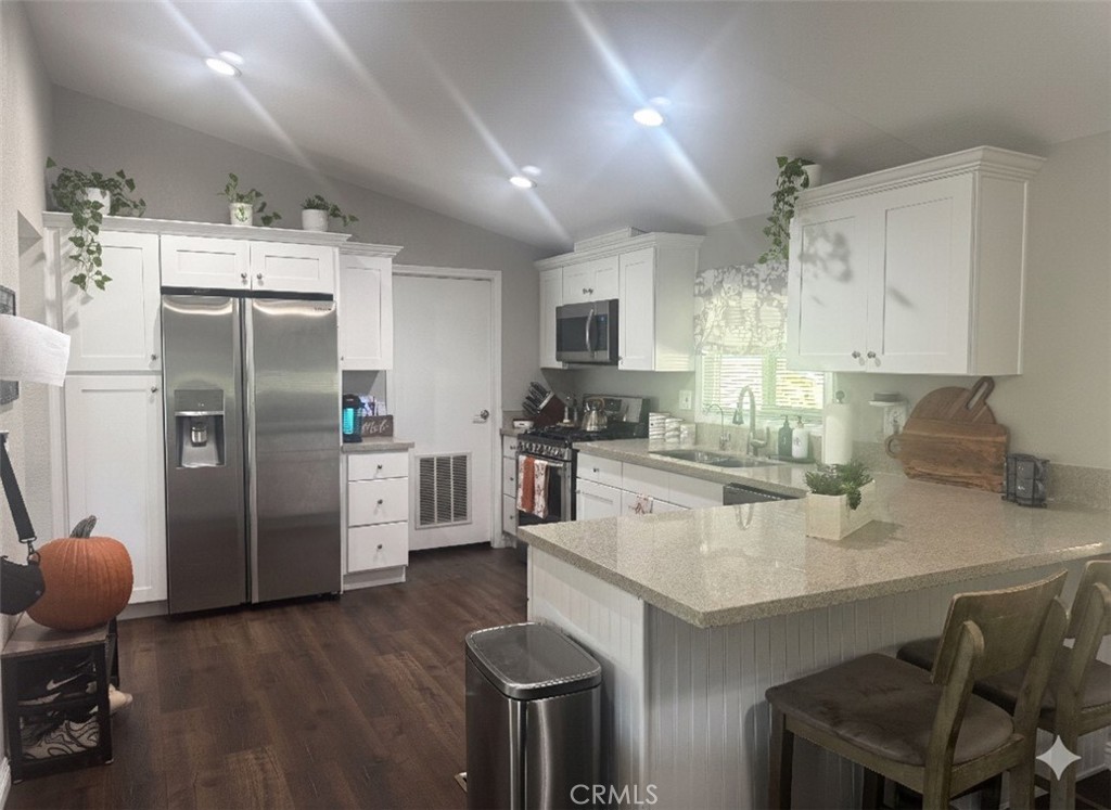 15181 Van Buren Boulevard, Unit 47 Riverside, CA 92504 - Photo 4 of 20 a kitchen with stainless steel appliances a refrigerator a stove a sink a dining table and chairs with wooden floor