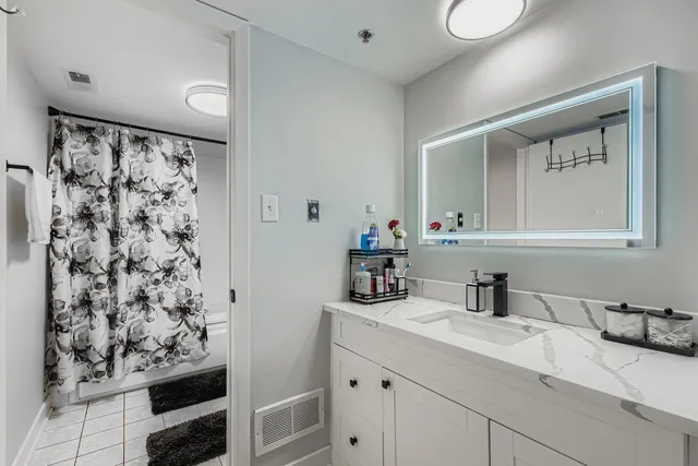 a bathroom with a granite countertop sink a mirror and shower
