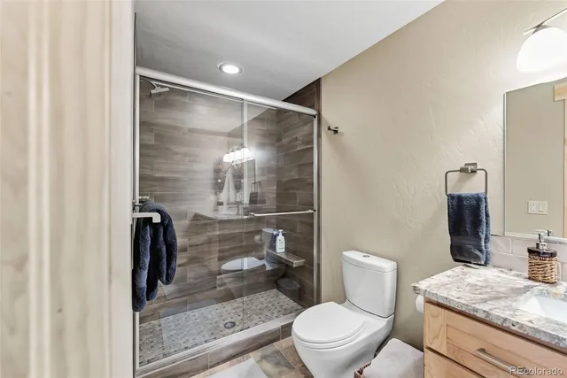 a bathroom with a granite countertop toilet a sink and shower