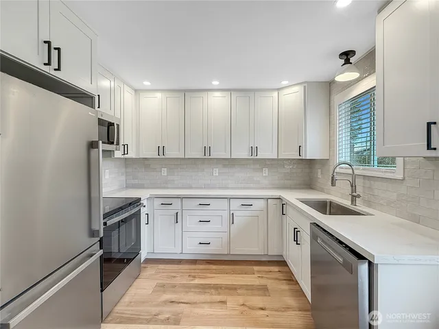 a kitchen with granite countertop a sink stainless steel appliances and cabinets