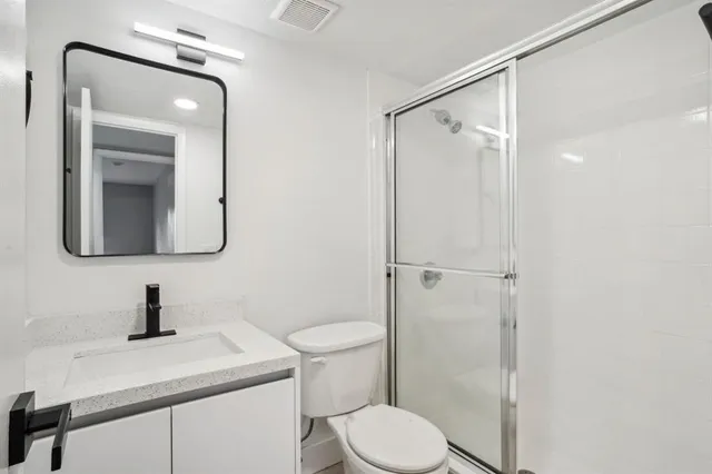 a bathroom with a toilet sink vanity and mirror