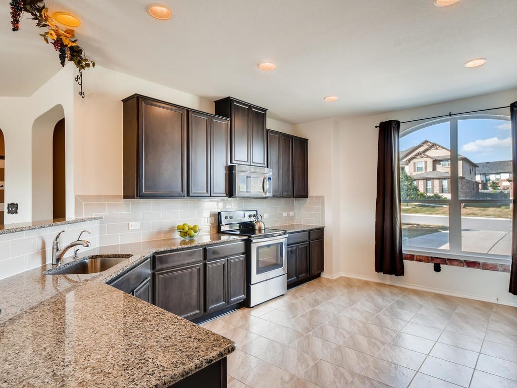 1301 Autumn Sage Way Pflugerville, TX 78660 - Photo 13 of 28 a kitchen with stainless steel appliances granite countertop a sink stove and refrigerator