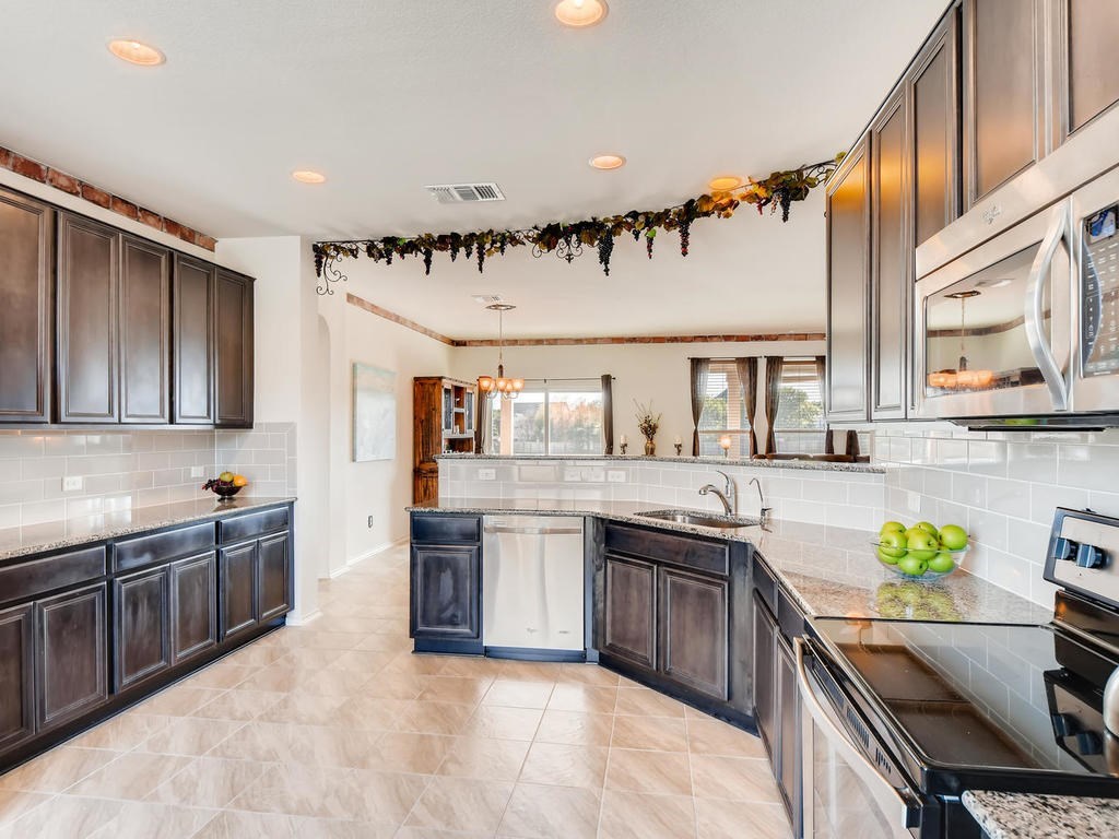 1301 Autumn Sage Way Pflugerville, TX 78660 - Photo 19 of 28 a kitchen with stainless steel appliances granite countertop a sink and stove