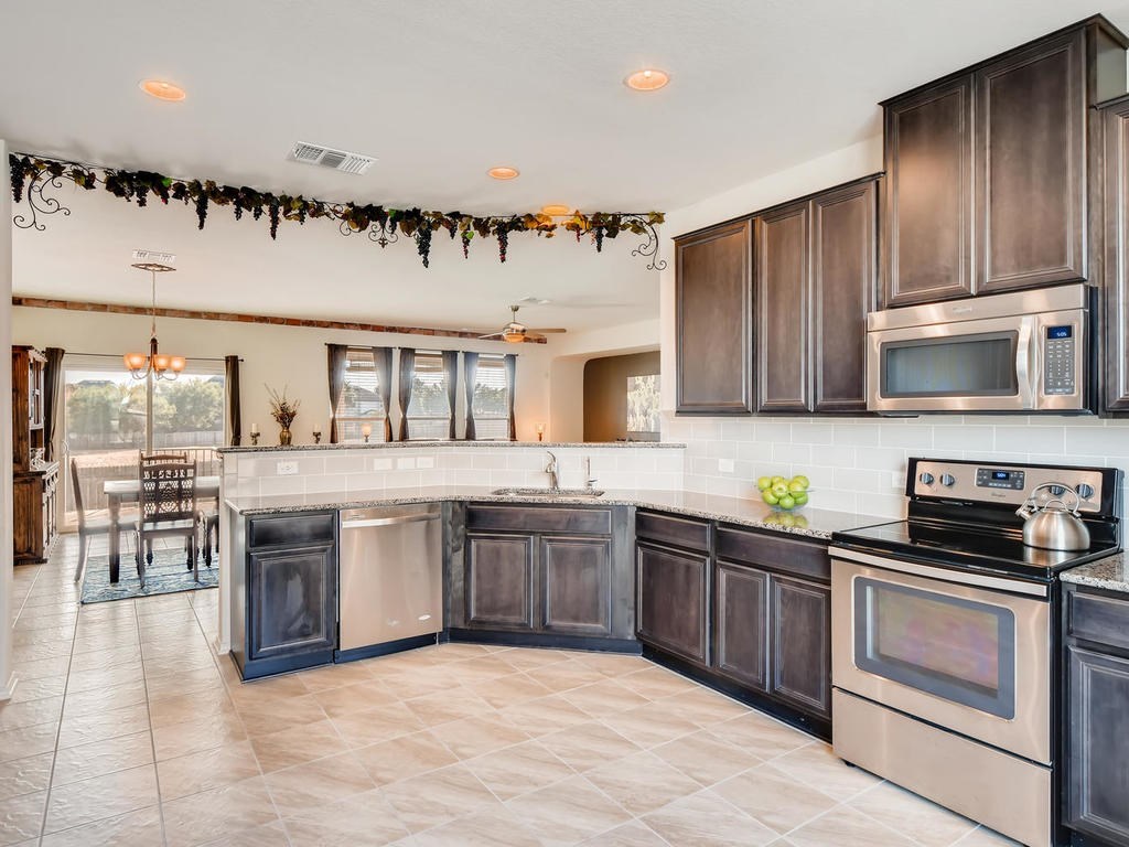 1301 Autumn Sage Way Pflugerville, TX 78660 - Photo 5 of 28 a kitchen with stainless steel appliances granite countertop a stove a sink and a microwave