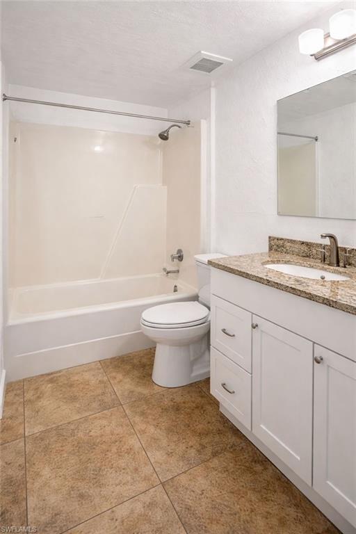 5324 Treetops Drive, Unit G2 Naples, FL 34113 - Photo 6 of 6 Bathroom with vanity, shower combination, a textured ceiling, a textured wall, and light tile patterned floors