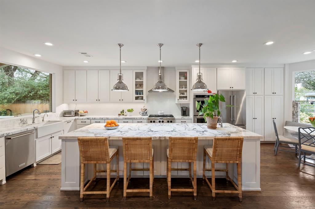 6605 Robin Road Dallas, TX 75209 - Photo 7 of 28 a kitchen with stainless steel appliances kitchen island granite countertop a dining table chairs and white cabinets