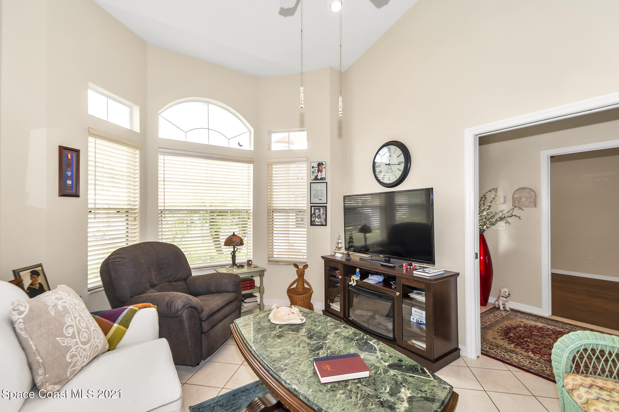 569 Renaissance Avenue Melbourne, FL 32940 - Photo 25 of 34 a living room with furniture a flat screen tv and a floor to ceiling window