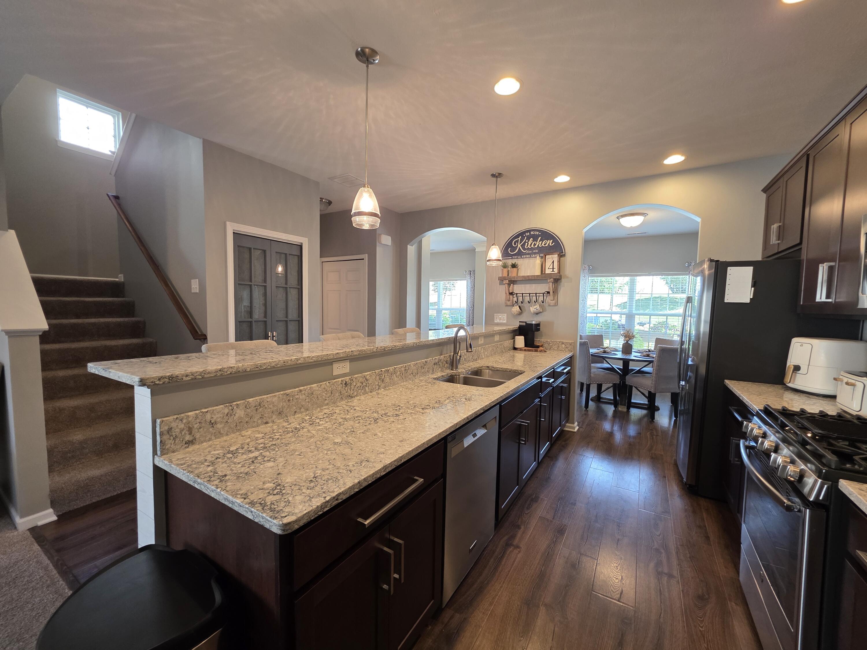 11558 Kentucky Street Crown Point, IN 46307 - Photo 12 of 39 a kitchen with a stove a sink wooden floor dining table and chairs