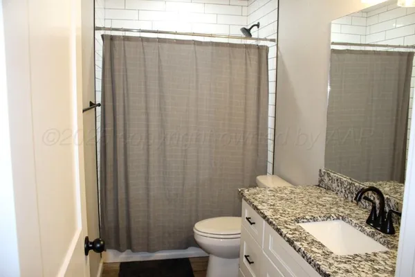 a bathroom with a granite countertop sink toilet and shower