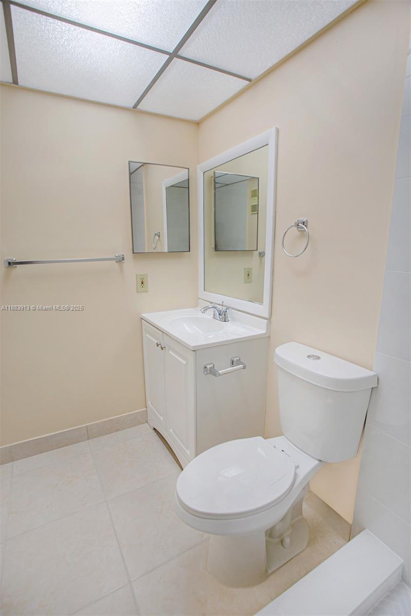 9711 West McNab Road, Unit 203 Tamarac, FL 33321 - Photo 16 of 37 a bathroom with a toilet a sink and mirror