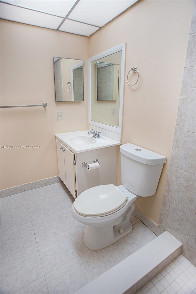 9711 West McNab Road, Unit 203 Tamarac, FL 33321 - Photo 22 of 37 a bathroom with a toilet a sink and mirror