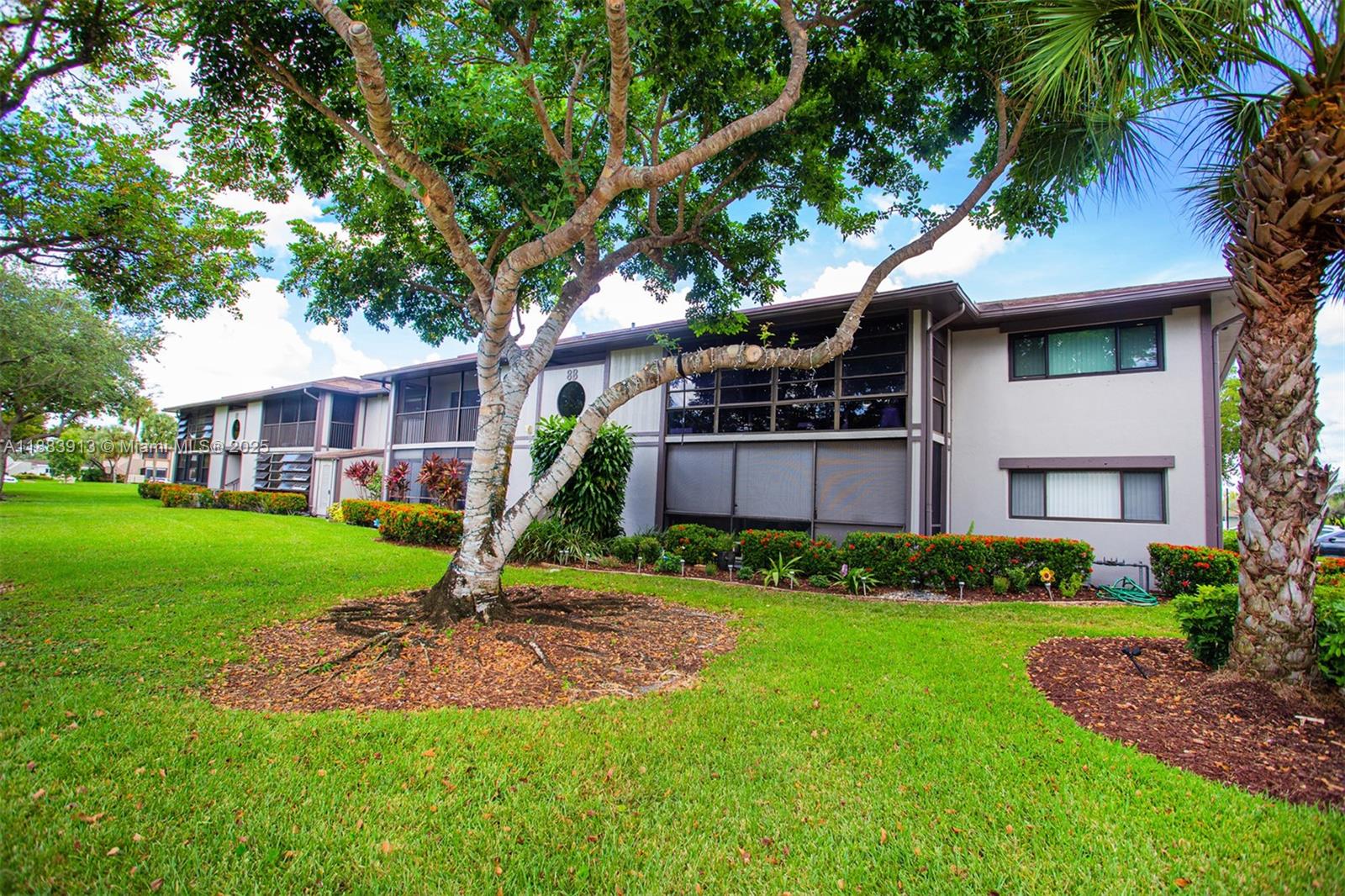 9711 West McNab Road, Unit 203 Tamarac, FL 33321 - Photo 26 of 37 a front view of a house with a yard and trees