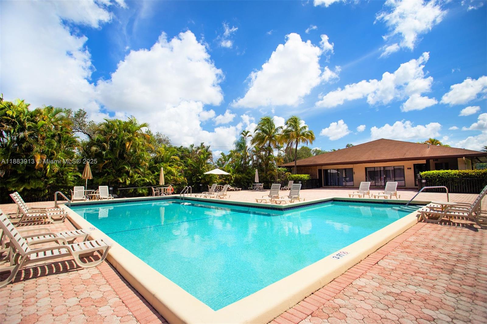 9711 West McNab Road, Unit 203 Tamarac, FL 33321 - Photo 32 of 37 a view of a swimming pool with lawn chairs under an umbrella
