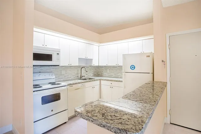 a kitchen with granite countertop white cabinets and white appliances