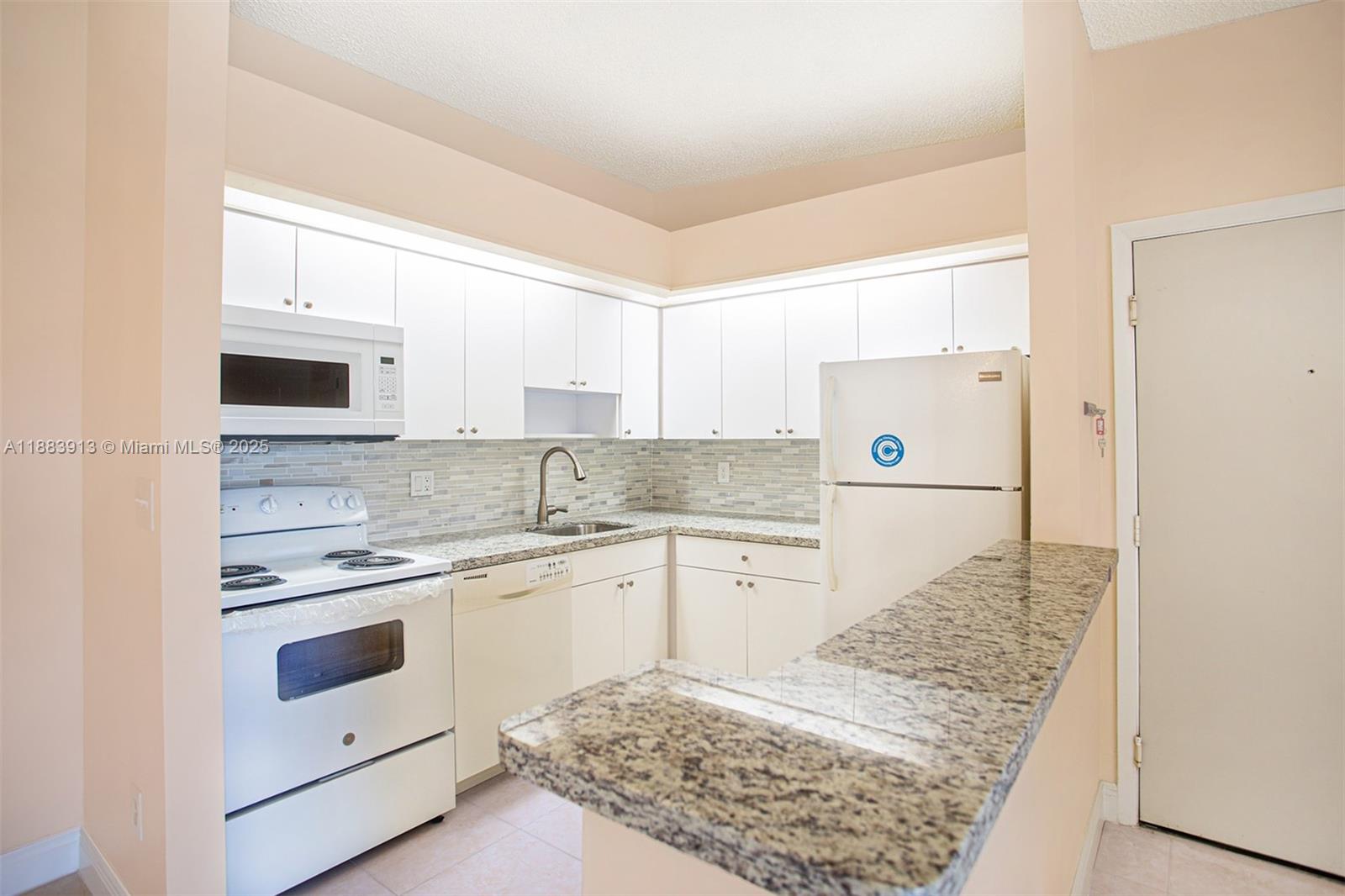 9711 West McNab Road, Unit 203 Tamarac, FL 33321 - Photo 5 of 37 a kitchen with white cabinets and white appliances