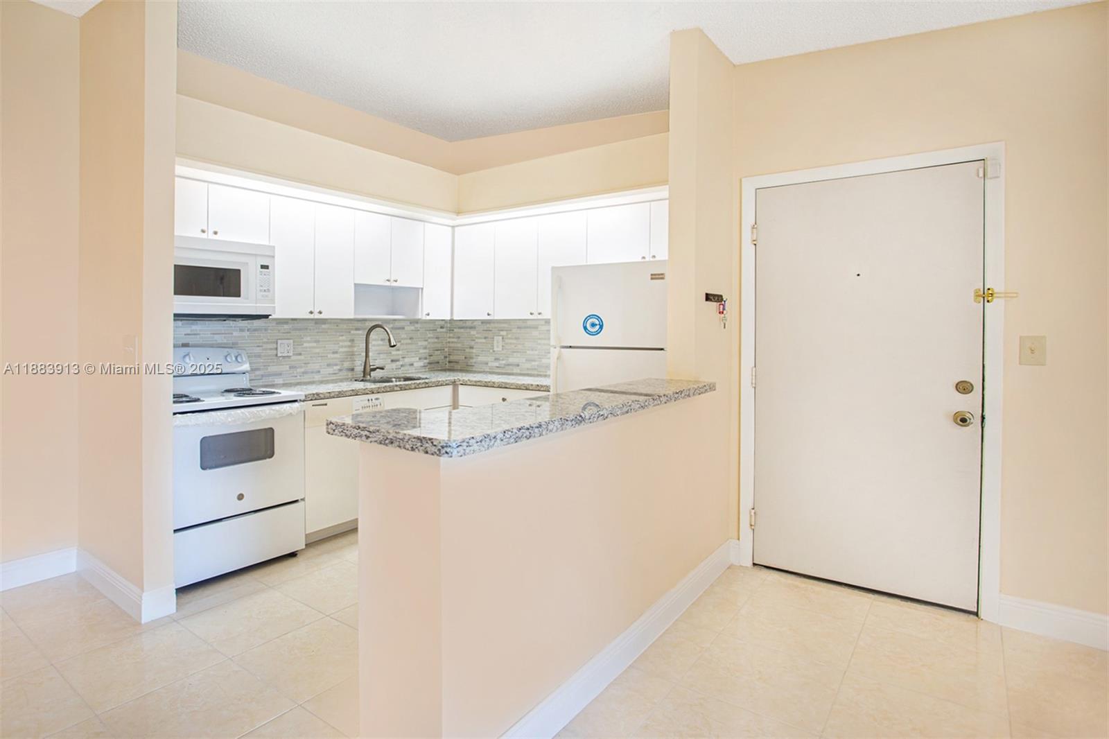 9711 West McNab Road, Unit 203 Tamarac, FL 33321 - Photo 6 of 37 a kitchen with granite countertop white cabinets and white appliances