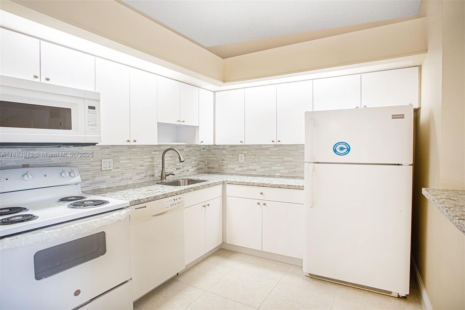 9711 West McNab Road, Unit 203 Tamarac, FL 33321 - Photo 8 of 37 a kitchen with a sink a stove and white cabinets