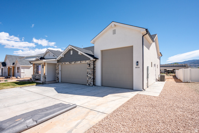 4978 North 75 East Enoch, UT 84721 - Photo 40 of 60 View of front of home with an attached garage, driveway, stucco siding, a residential view, and stone siding